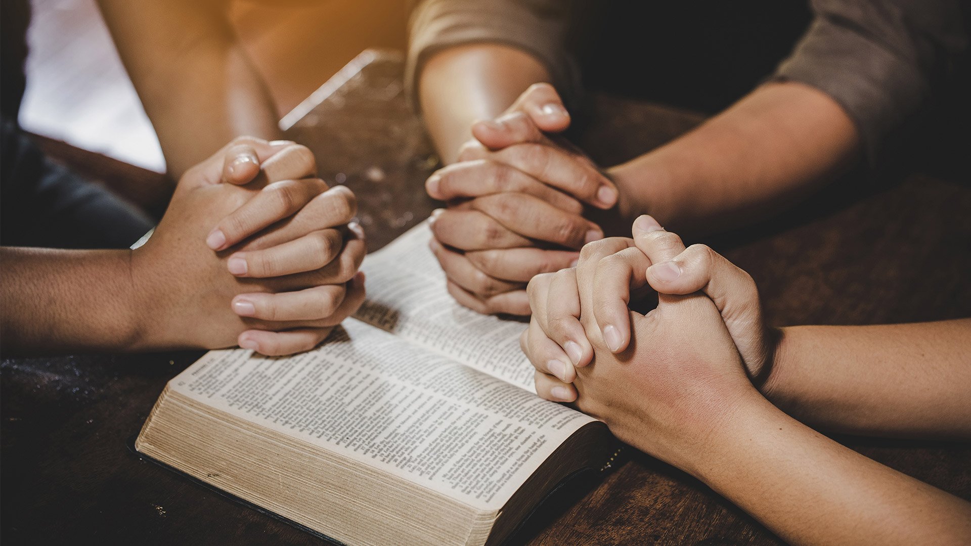 Hands praying on Bible